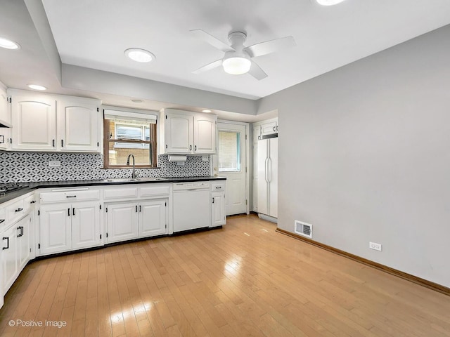 kitchen with white appliances, visible vents, a sink, dark countertops, and tasteful backsplash