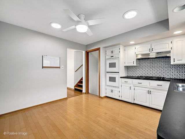 kitchen featuring white cabinetry, double oven, gas stovetop, and under cabinet range hood