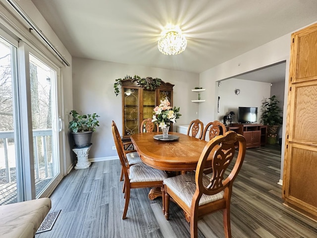 dining area featuring dark hardwood / wood-style flooring, a healthy amount of sunlight, and an inviting chandelier