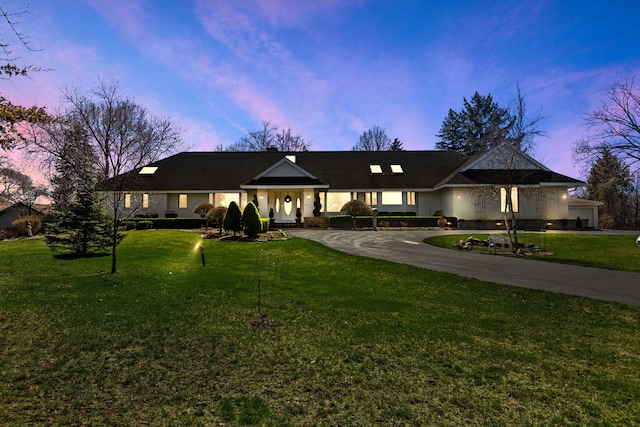 ranch-style home featuring a garage and a lawn