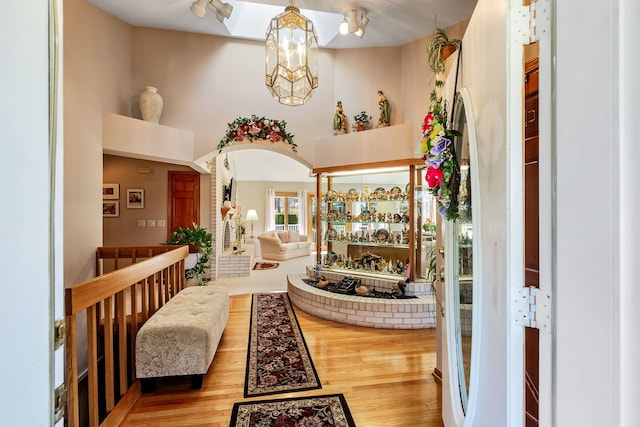 entryway featuring wood-type flooring, a towering ceiling, and an inviting chandelier