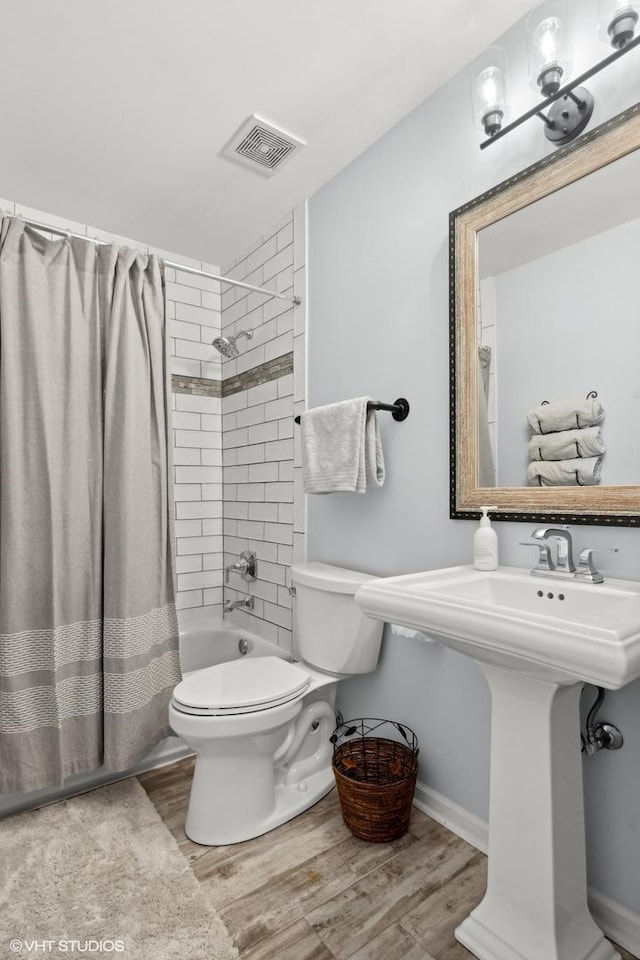 bathroom featuring hardwood / wood-style floors, shower / bath combo with shower curtain, and toilet