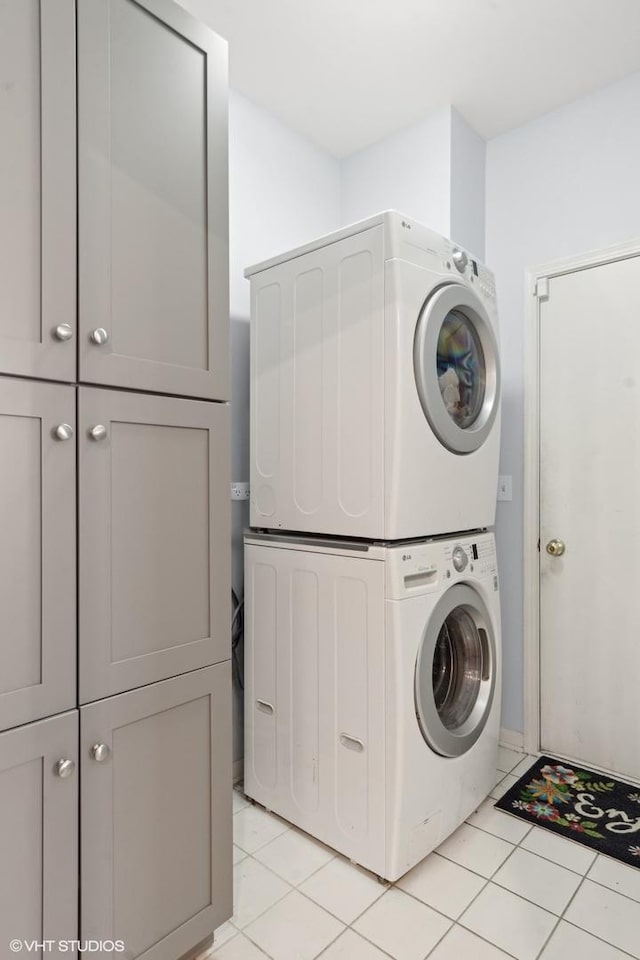 washroom with cabinets, stacked washer and dryer, and light tile patterned flooring