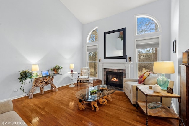 living room with hardwood / wood-style floors, a wealth of natural light, high vaulted ceiling, and a tile fireplace