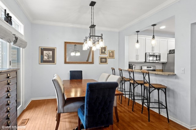 dining space with crown molding, hardwood / wood-style flooring, and an inviting chandelier