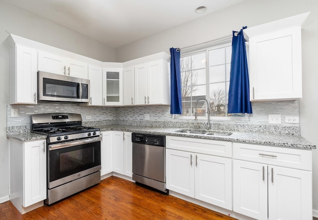 kitchen featuring stainless steel appliances, white cabinetry, light stone countertops, and sink