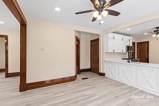 unfurnished living room featuring light wood-type flooring, sink, and ceiling fan