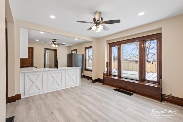 interior space with sink, ceiling fan, and light hardwood / wood-style flooring