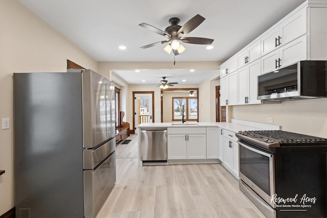 kitchen featuring stainless steel appliances, white cabinets, light hardwood / wood-style floors, sink, and kitchen peninsula