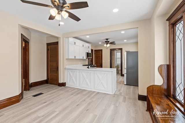 kitchen with stainless steel appliances, ceiling fan, light hardwood / wood-style floors, white cabinetry, and kitchen peninsula