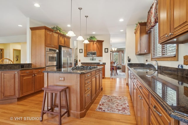 kitchen with a kitchen bar, decorative light fixtures, a kitchen island, stainless steel appliances, and light hardwood / wood-style floors