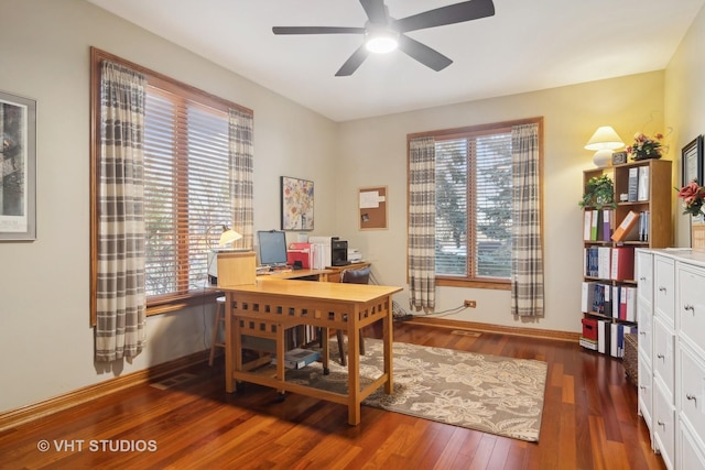 home office with dark wood-type flooring, ceiling fan, and a healthy amount of sunlight