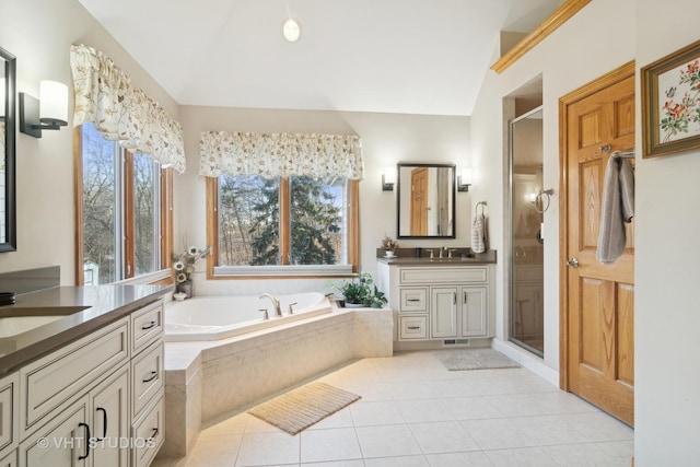 bathroom featuring vaulted ceiling, vanity, plus walk in shower, and tile patterned flooring