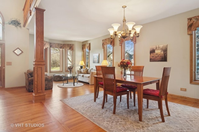 dining space with a chandelier, light hardwood / wood-style flooring, and ornate columns