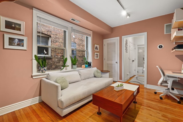 living room featuring rail lighting and light hardwood / wood-style floors