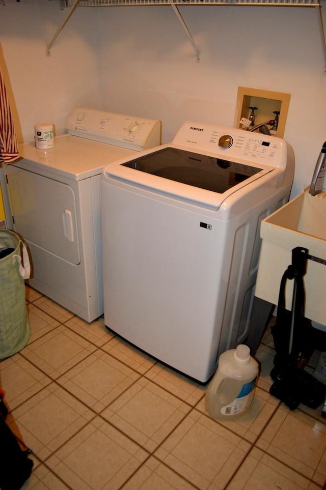 laundry room with washer and dryer, laundry area, a sink, and light tile patterned flooring