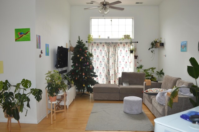 living room featuring light wood finished floors, a ceiling fan, and visible vents