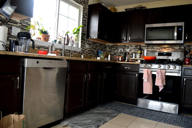 kitchen featuring dark cabinetry, tile patterned floors, appliances with stainless steel finishes, and decorative backsplash