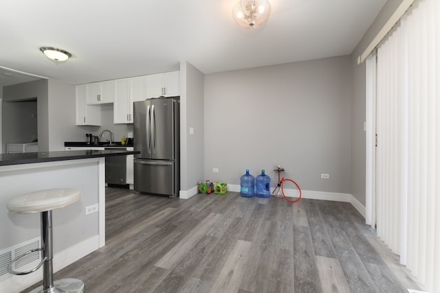 kitchen with hardwood / wood-style floors, stainless steel refrigerator, a breakfast bar area, white cabinets, and kitchen peninsula