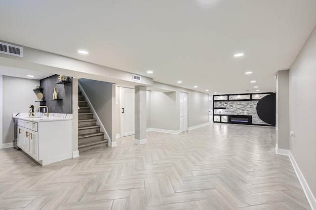 basement with sink, a fireplace, and light parquet flooring