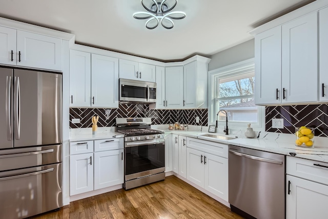 kitchen featuring stainless steel appliances, sink, white cabinets, and light hardwood / wood-style floors