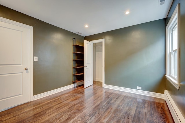 unfurnished bedroom featuring a baseboard radiator and wood-type flooring