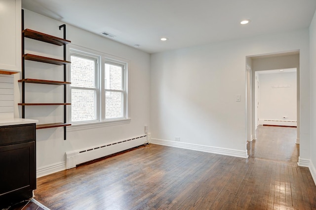 spare room with a baseboard radiator and dark hardwood / wood-style flooring