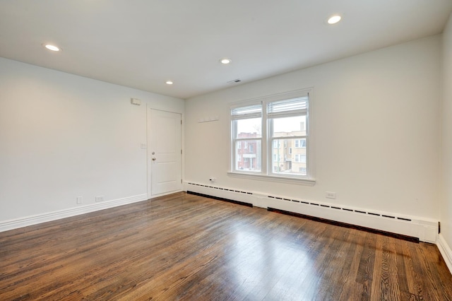 unfurnished room featuring dark hardwood / wood-style flooring and a baseboard heating unit