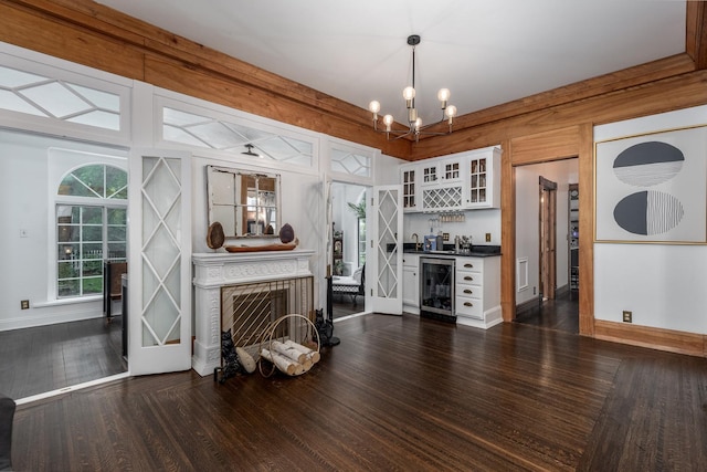 living room with wine cooler, a notable chandelier, dark wood-type flooring, and indoor bar