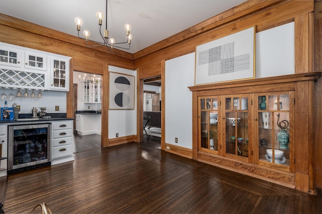 bar featuring dark wood-type flooring, white cabinetry, an inviting chandelier, wine cooler, and decorative light fixtures