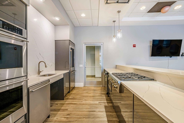 545 N Dearborn St Unit 2709, Chicago, IL 60654 - kitchen featuring stainless steel appliances, a sink, pendant lighting, light wood finished floors, and light stone countertops