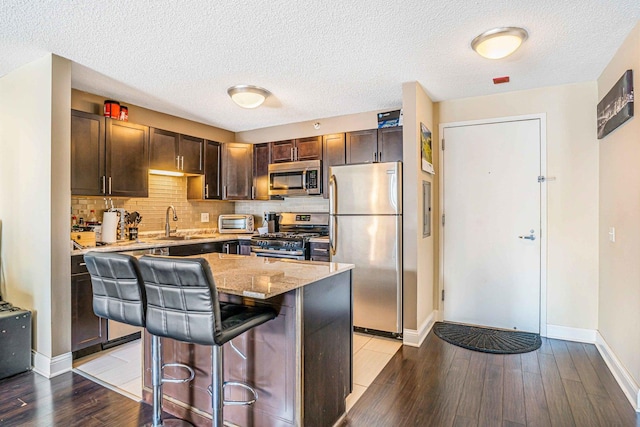 545 N Dearborn St Unit 2709, Chicago, IL 60654 - kitchen featuring light wood-style flooring, stainless steel appliances, a sink, light stone counters, and a breakfast bar area