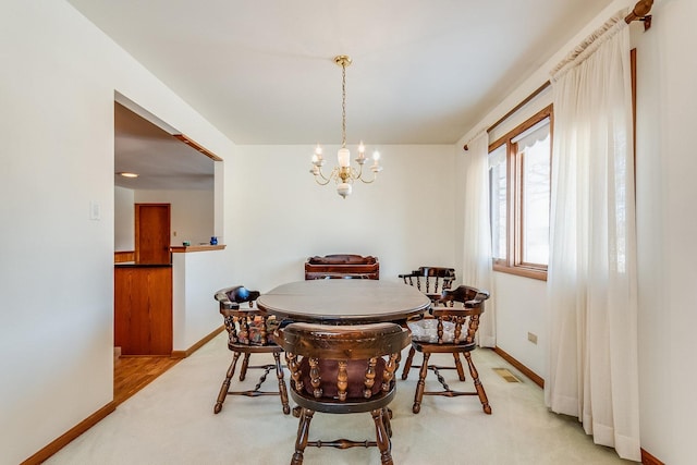 dining space featuring baseboards, light colored carpet, visible vents, and a notable chandelier