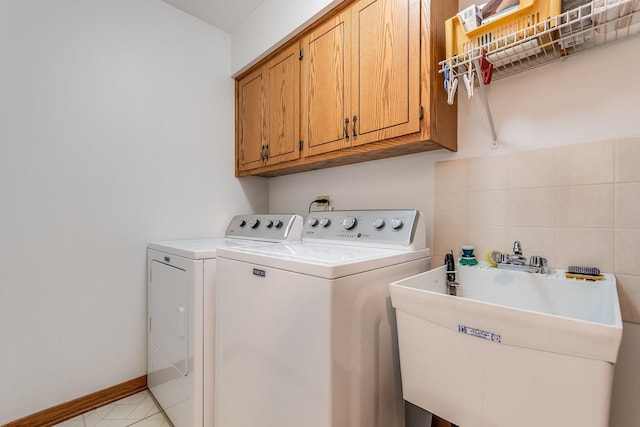 laundry area featuring cabinet space, a sink, washer and clothes dryer, and baseboards