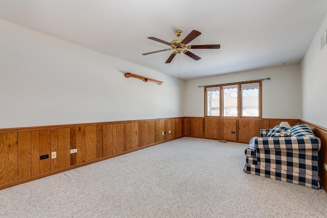 unfurnished room featuring a wainscoted wall, wood walls, and light colored carpet