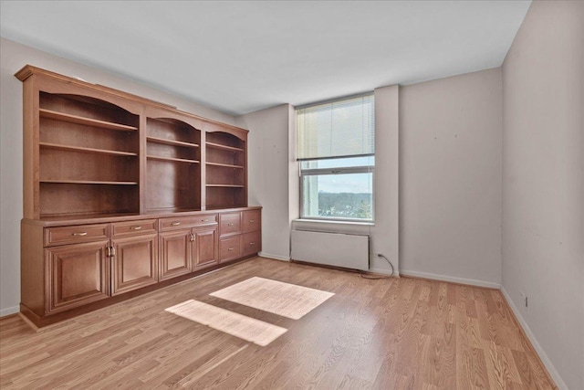 empty room with radiator heating unit, light wood-style flooring, and baseboards