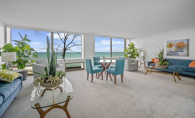 living area with light carpet, ornamental molding, a water view, and floor to ceiling windows