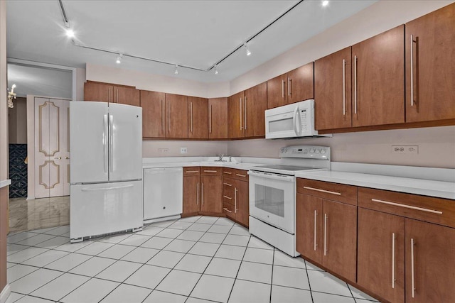 kitchen featuring brown cabinets, white appliances, light tile patterned floors, and light countertops