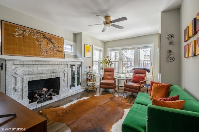 living room featuring a brick fireplace, ceiling fan, and wood-type flooring