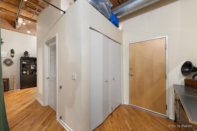 hall featuring wood-type flooring and a towering ceiling