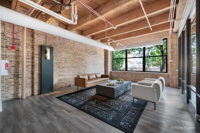 living room with wood ceiling, track lighting, elevator, brick wall, and beamed ceiling