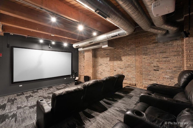 cinema room featuring rail lighting and brick wall