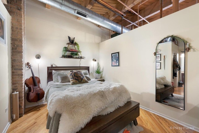 bedroom featuring a towering ceiling and hardwood / wood-style floors