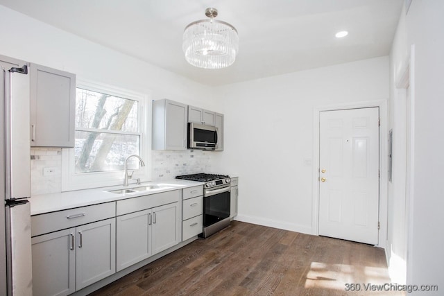 kitchen with dark wood-type flooring, sink, tasteful backsplash, gray cabinets, and stainless steel appliances