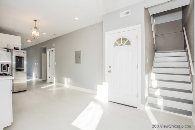 foyer entrance with electric panel and a chandelier