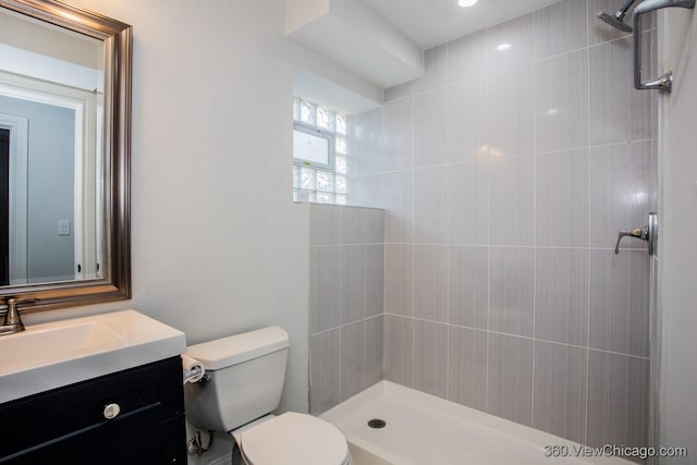 bathroom featuring vanity, a tile shower, and toilet