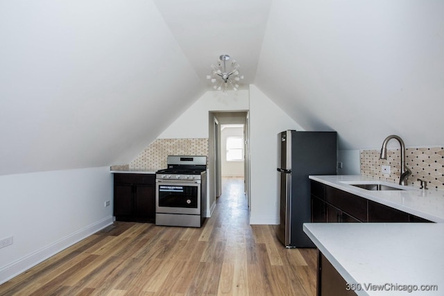 kitchen featuring vaulted ceiling, appliances with stainless steel finishes, light hardwood / wood-style floors, and sink