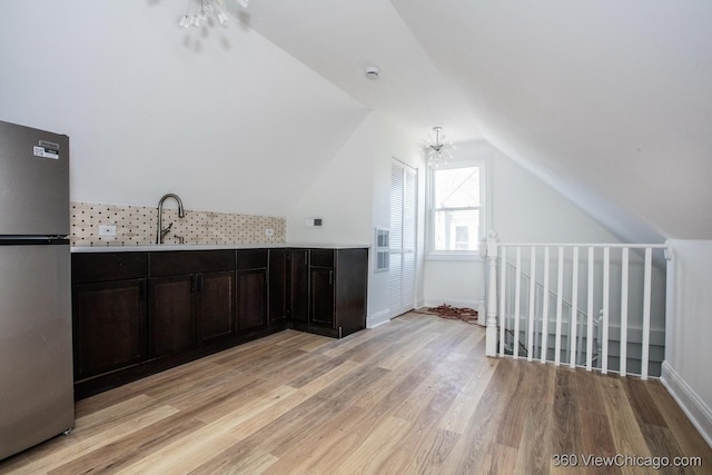 bonus room featuring lofted ceiling, sink, a notable chandelier, and light hardwood / wood-style flooring