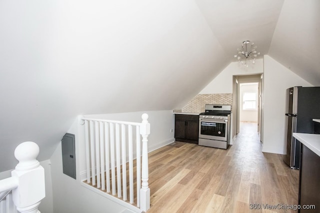 kitchen featuring an inviting chandelier, lofted ceiling, stainless steel appliances, and light hardwood / wood-style flooring