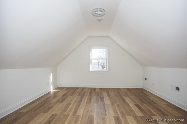 additional living space featuring wood-type flooring and vaulted ceiling